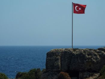 Turkish flag waving on cliff by sea