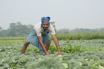 Full length of a young farmer working in vegetable field