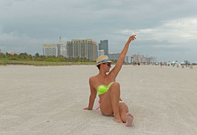 Full length of young woman on beach against sky