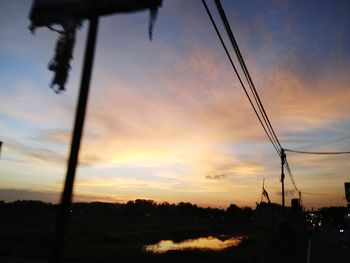 Low angle view of silhouette electricity pylon against sky during sunset