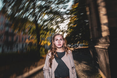 Portrait of beautiful young woman standing against trees