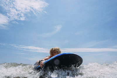 Carefree girl surfing on sea against sky