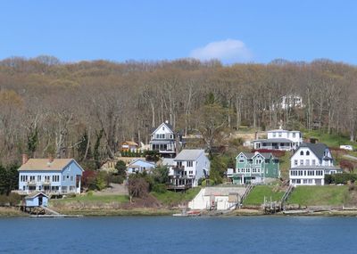 Houses by river and buildings against sky