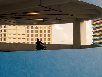 Man sitting against building in city