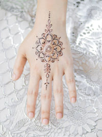 Close-up of woman hand with tattoo on bed