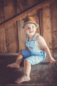 Full length of boy sitting on table in barn