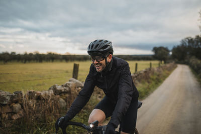 Happy man wearing cycling helmet riding bicycle on road