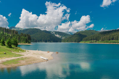 Scenic view of lake and mountains against blue sky