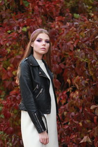 Portrait of young woman wearing leather jacket while standing in forest