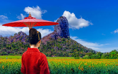 Rear view of man standing on field against sky