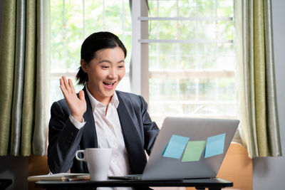 Portrait of smiling young woman using laptop on table