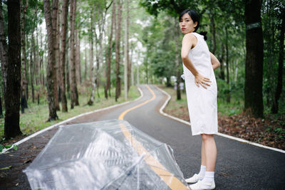 Full length of woman standing on road in forest