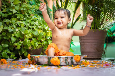 Cute toddler baby boy bathing in decorated bathtub at outdoor from unique perspective