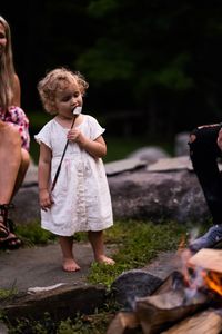 Cute girl eating marshmallow in skewer while standing on land
