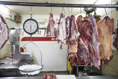 Meat and scale hanging on display at market butcher shop.