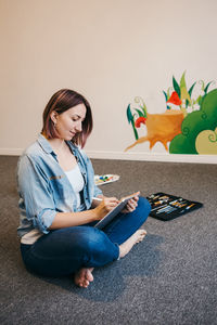 Young woman sitting on wall at home