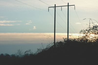 Scenic view of power lines against sky at sunset