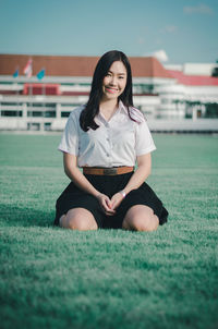 Portrait of smiling young woman sitting on land