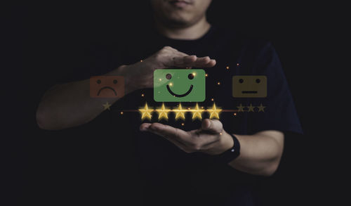 Midsection of man holding toy against black background