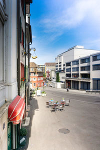 Cars on street by buildings against sky in city