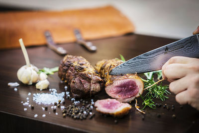 Close-up of hand holding food on cutting board