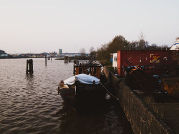 Boats moored on river against clear sky