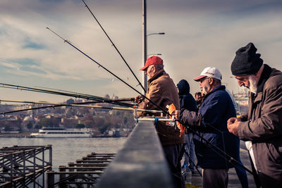 Men standing by sea against sky in city