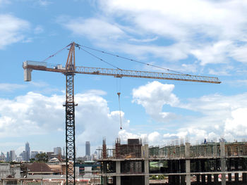 Cranes at construction site against sky in city