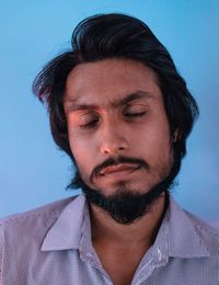 Close-up of man sleeping against blue background