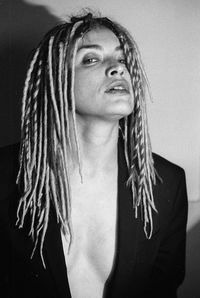 Close-up portrait of young woman with dreadlocks against wall