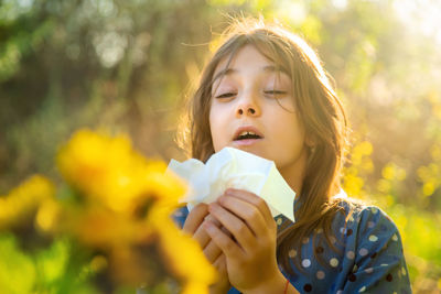 Girl holding tissue paper sneezing in garden