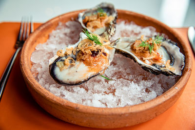 Fresh oysters in shell topping with fried shallot, chili paste, dill and thai style seafood sauce