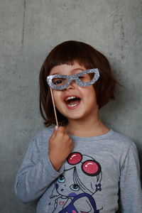 Portrait of girl wearing sunglasses against wall