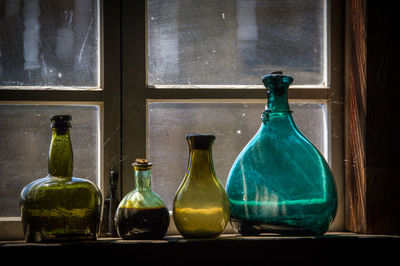 Close-up of glass bottles on window sill