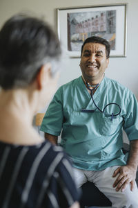 Happy male doctor with senior patient in clinic