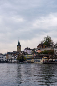 Buildings by river against sky