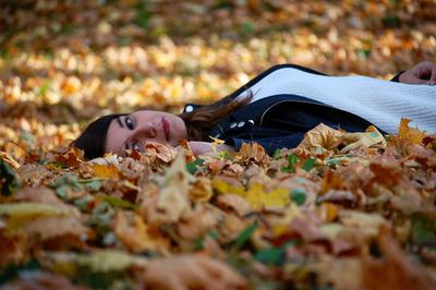 Portrait of woman lying on leaves during autumn