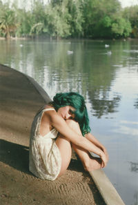 Woman sitting by lake