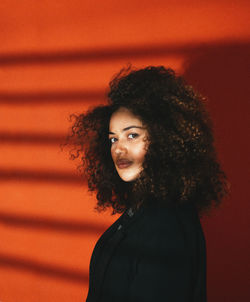 Portrait of young woman standing against wall