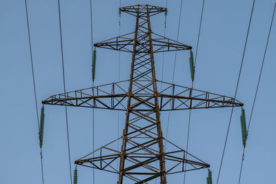 Low angle view of electricity pylon against clear blue sky