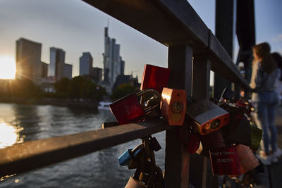 Close-up of padlocks on railing by river in city