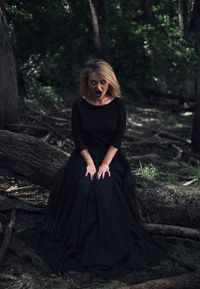 Woman with blind eyes sitting on tree in forest