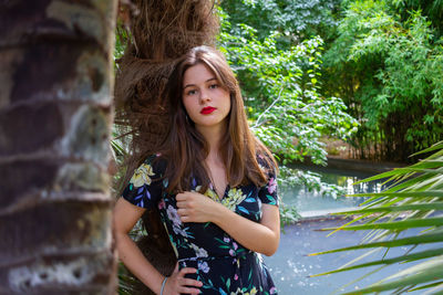 Portrait of beautiful young woman against plants