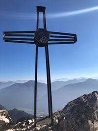 Cross on mountains against blue sky