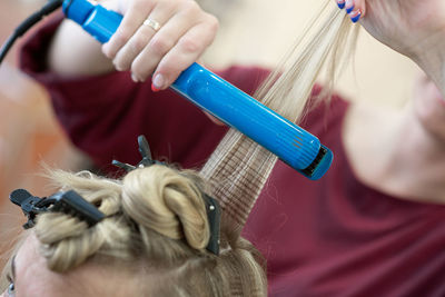 Close-up of hair dresser shaping customer hair at salon