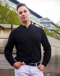 Portrait of young man standing against building
