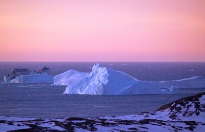 Icebergs floating on sea against sky during sunset