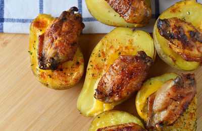 High angle view of baked potato with barbecue chicken wings 