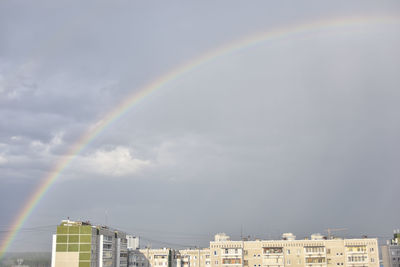 Rainbow over buildings in city against sky
