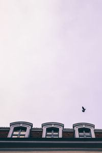 Low angle view of building against clear sky with freedom dove flying over it